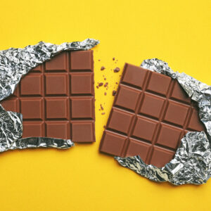 parts of delicious chocolate bar on yellow background, flat lay