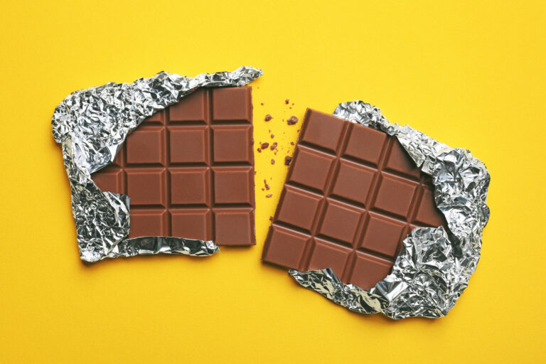 parts of delicious chocolate bar on yellow background, flat lay