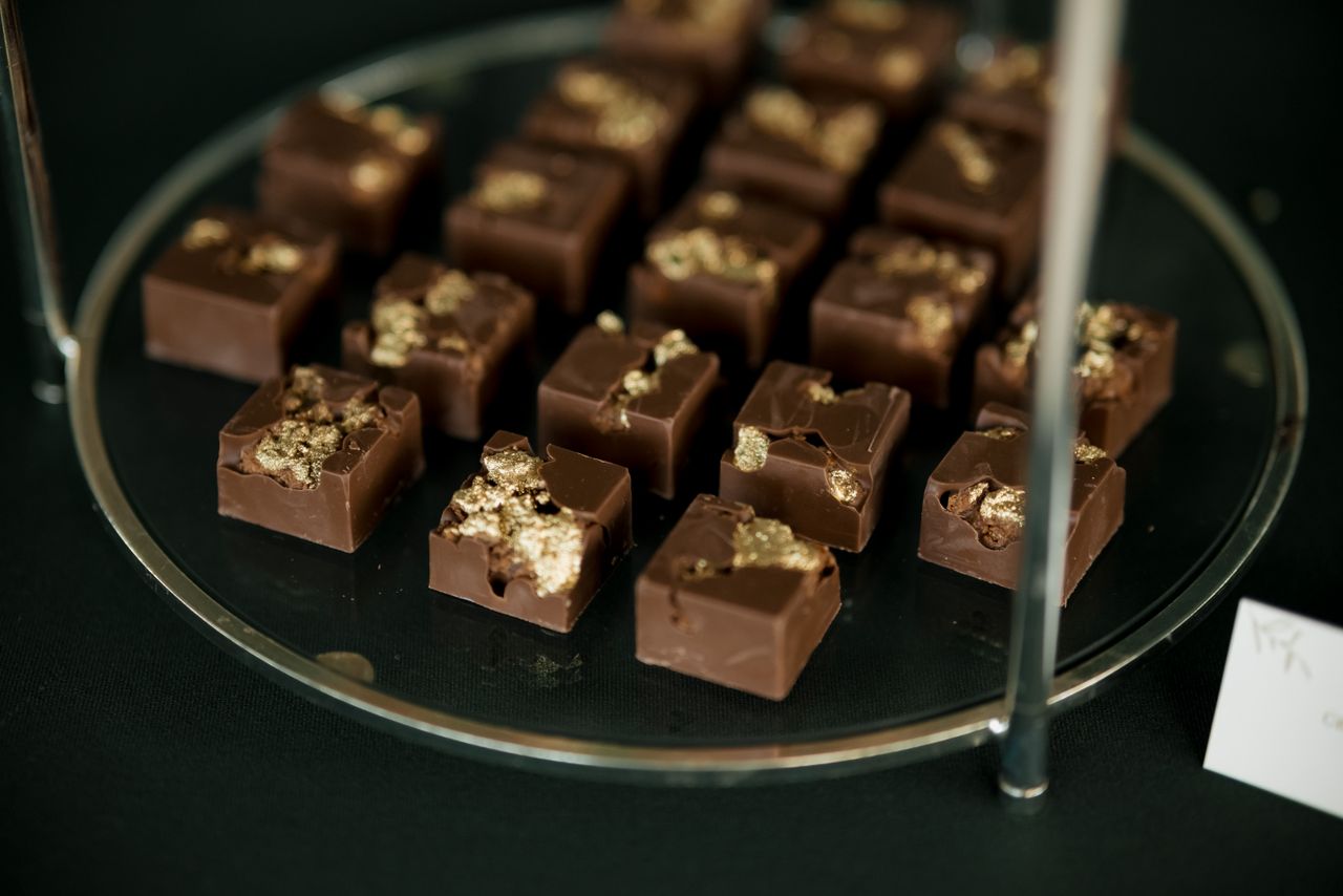 Elegant dark chocolates adorned with gold flakes arranged on a display stand.